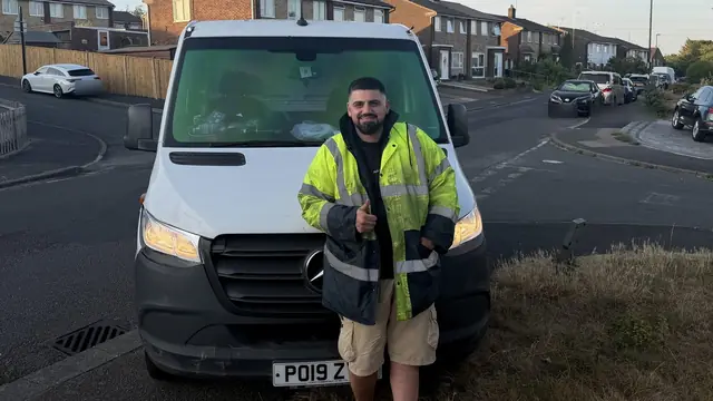 A driver standing at the front of a recovery truck