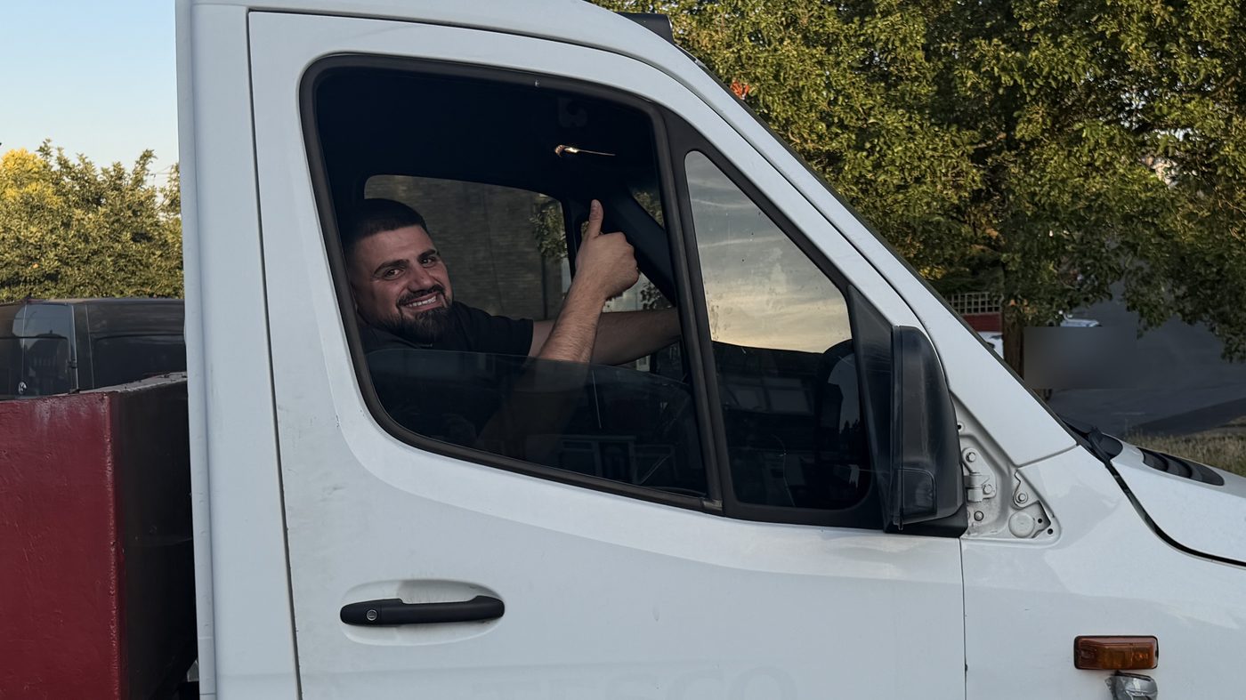 A driver at the wheel of a recovery truck, window down